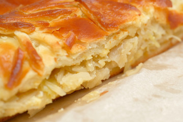 Pie from dough with cabbage on craft paper. Close up.