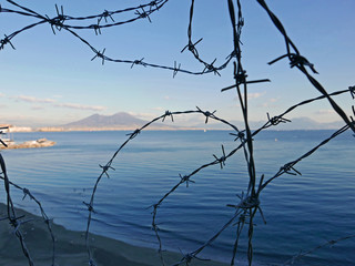 suggestiva vista del mare di napoli attraverso un filo spinato