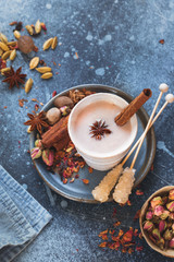 Spiced traditional Indian masala chai tea in cup with spices on rustic background