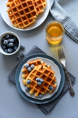 Belgian waffles with blueberries and honey on gray wooden background. Homemade healthy breakfast. Selective focus