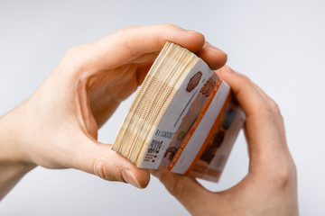 Stack of banknotes five thousand russian rubles in man's hand isolated on white background. Bundle...