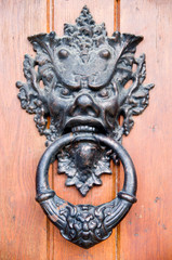 Decorative door knocker with scary face on wooden door , Bulgaria