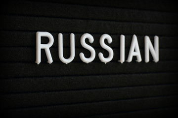 The word Russian in white plastic letters on a black notice board 