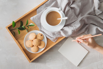 Male hands writing post card on the stone table with cup of coffee and cookie. Business with love concept.