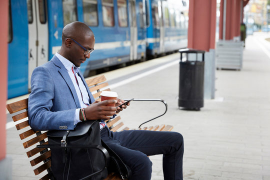 Businessman using smartphone at railway station