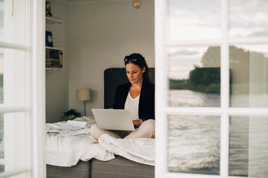 Businesswoman using laptop while sitting on bed at home