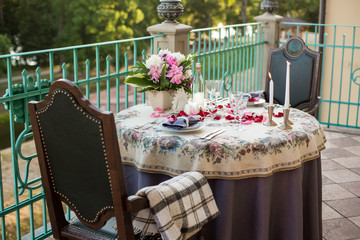 Wedding, anniversary, valentine romantic decor of the festive table in the restaurant with candles, flowers, peonies, rose petals, branches, empty wine glasses on old vintage table