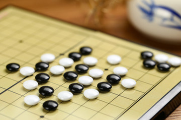 Chinese go game board, close up view of playing black and white stone pieces
