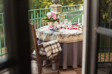 Wedding, anniversary, valentine romantic decor of the festive table in the restaurant with candles, flowers, peonies, rose petals, branches, empty wine glasses on old vintage table