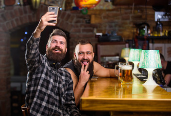 Send selfie to friends social networks. Man in bar drinking beer. Take selfie photo to remember great evening in pub. Online communication. Man bearded hipster hold smartphone. Taking selfie concept