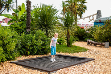 Blonde boy with glasses 7 years old jumping in the children playground in the entertainment park