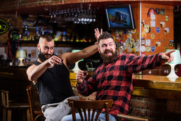 Cheers concept. Hipster brutal bearded man drinking alcohol with friend at bar counter. Men drunk relaxing at pub having fun. Strong alcohol drinks. Friends relaxing in pub. Friday relax in pub