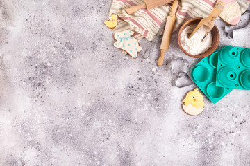 Fototapeta na wymiar Baking accessories on stone background with flour and easter glazed cookies . Easter preparation or baking sweets, flat lay with copy space