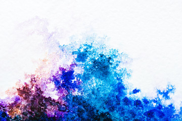 top view of blue and purple watercolor spills on white paper