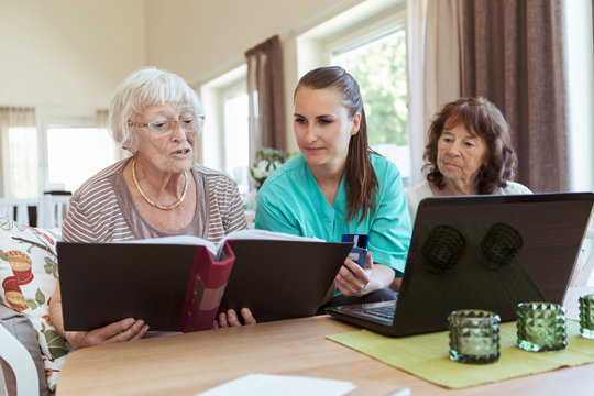 Nurse helping senior women to pay online bills at home