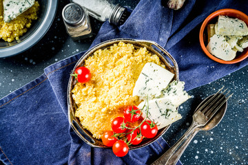 Lombardy italian food, Polenta corn porridge with tomatoes  with gorgonzola cheese, dark blue background copy space