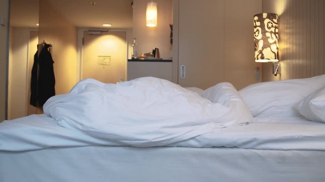 Young Woman Playing Peekaboo From Under Bed Sheets