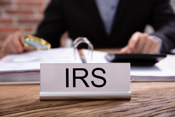 Nameplate With IRS Title Kept On Businessman Desk