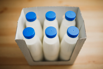 milk bottles in cardboard box on wooden table