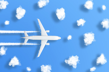 Model airplane design miniature on bight blue background with fluffy clouds and shadows objects. The idea of tickets for the trip, traveling by plane, new discoveries, summer holidays