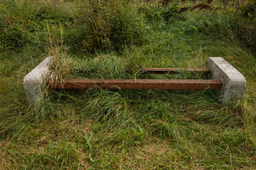 The abandoned and overgrown with grass bench in the park