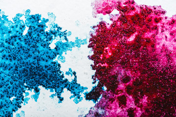 top view of blue and pink watercolor spills on white background