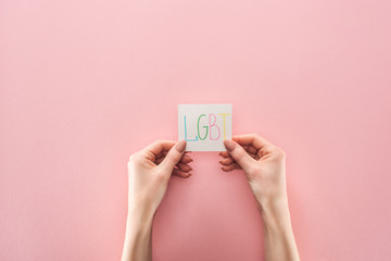 cropped view of woman holding card with "lgbt" handwritten abbreviation on pink background
