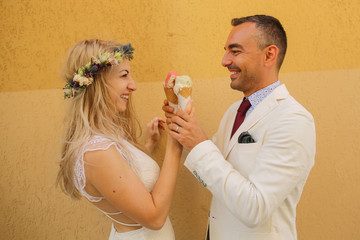 Beautiful wedding couple posing with ice creams in hands