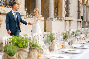 Wedding couple. Blonde bride and groom walking near old castle and garden