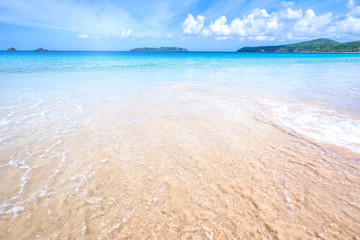 Beautiful amazing gold colored sandy beach with soft waves isolated with sunny blue sky. Concept of tropical calm tourism idea, copy space, close up