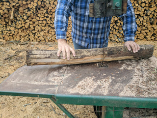 Worker cuts wood with bandsaw.