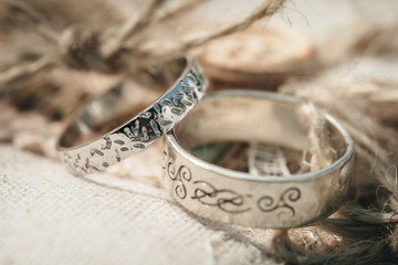 Wedding rings placed on a vintage decor of burlap and harmonious cords