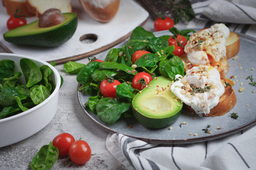 Toasts with avocado and poached egg, tomatoes and spinach, On a light gray background, Fresh morning breakfast