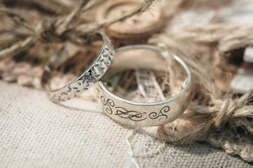 Wedding rings placed on a vintage decor of burlap and harmonious cords