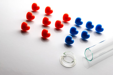 Failed in vitro fertilization. Broken test tube with a split neck. IVF. The letters composed of red and blue hearts on a white background. Copy space.