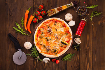 delicious Italian seafood pizza with ingredients on a dark wooden table (close top view).