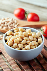 Cooked chickpeas (Cicer arietinum) in bowl on wooden background