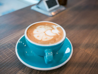 Hot coffee late art in cup on table, peacock in face hot coffee,