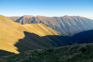Naklejka premium Part of the main ridge in Fagaras mountains, Romania (part of the Carpathian mountains) as seen during the golden hour, just before sunset, during a beautiful autumn day hiking trip, with blue skies
