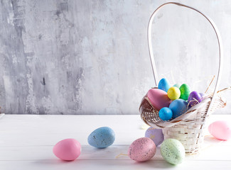 Easter basket filled with colorful hand painted Easter Eggs over a light background