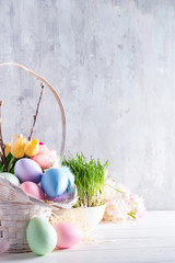 Easter basket filled with colorful hand painted Easter Eggs over a light background