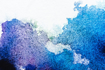 top view of blue and grey watercolor spills on white paper