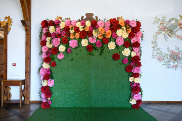 Stylish unusual wedding decoration photozone with green grasses and paper colorful flowers