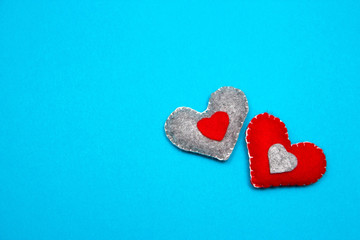 Two red felt handmade hearts on a blue background. Top view.