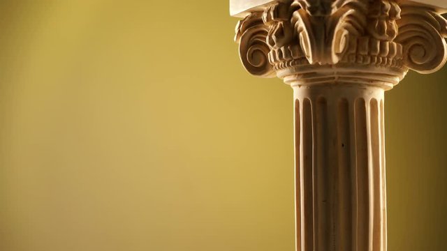 Single ancient corinthian column rotating slowly on bright background