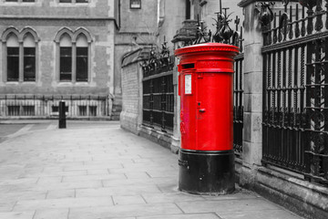 The traditional British red post box in London standing on the street. Isolated in a black and...