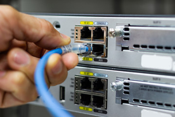 Hand of man holding The network cables to connect SFP module port in the Datacenter room, concept Communication technology