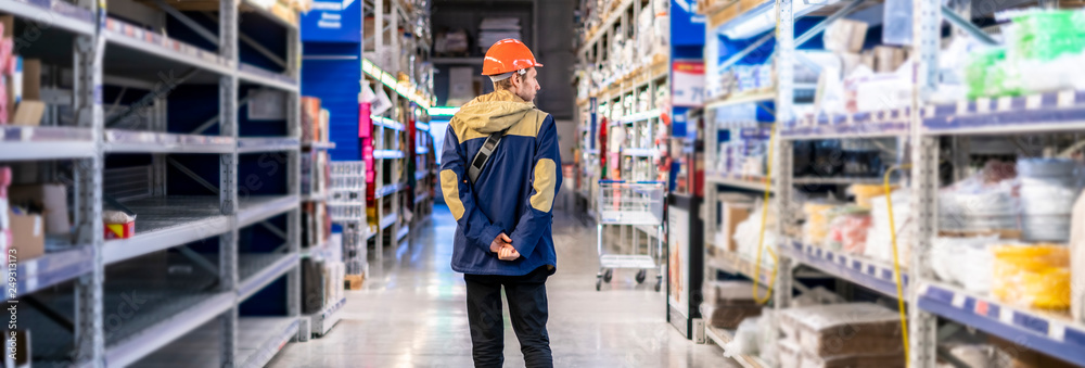 Wall mural young worker in protective helmet sort products at the market b