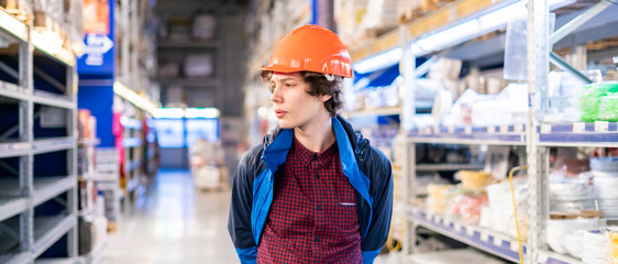 young worker in protective helmet sort products at the market b