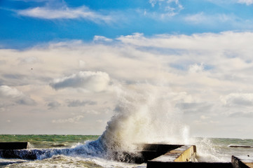 Naklejka na ściany i meble A huge wave and a man on the pier. Storm on the sea.